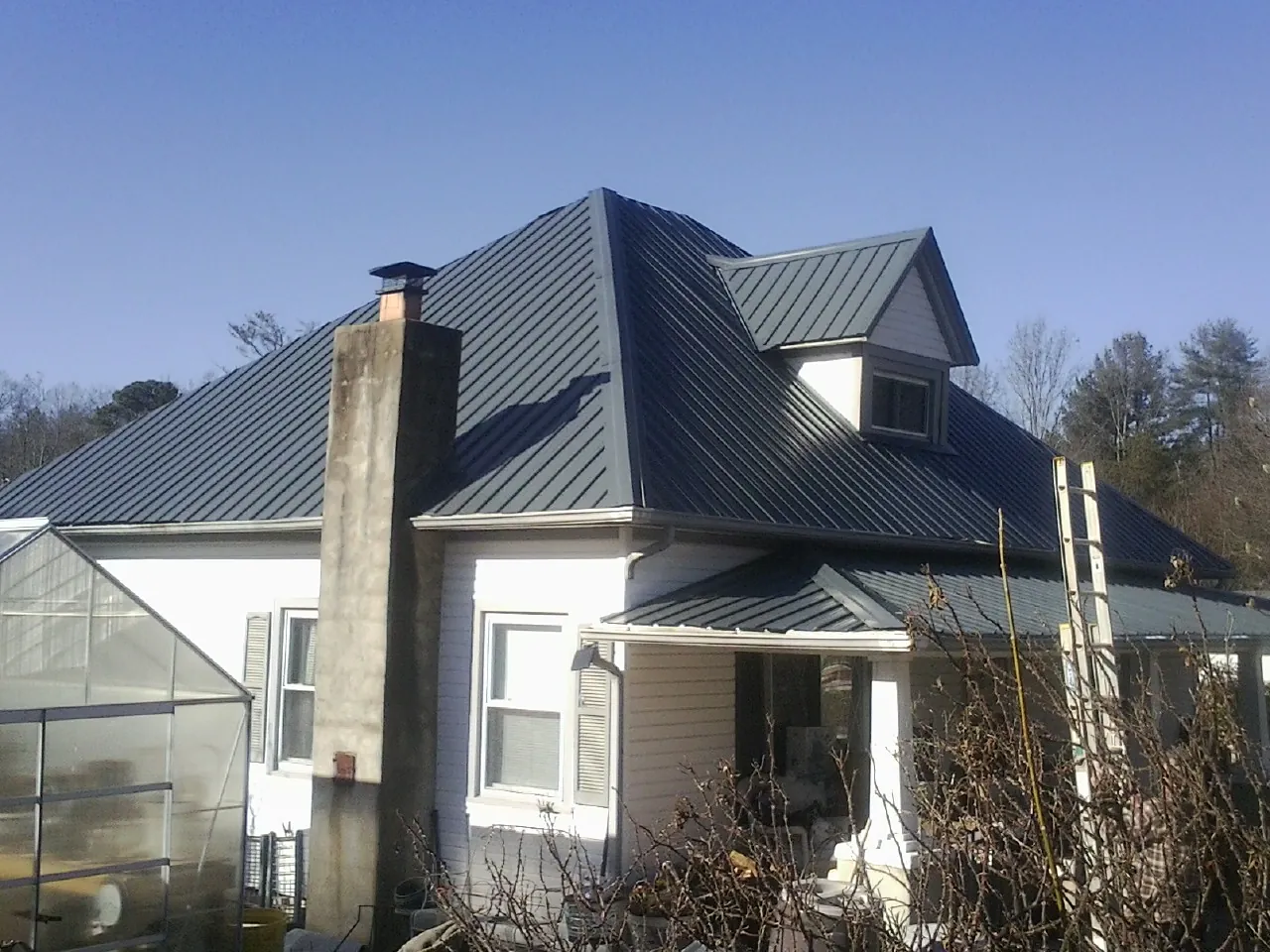 Dark blue standing seam metal roof on a white farmhouse with dormer — Slate & Tile Roof Repair by Roofing Brothers in Notre Dame