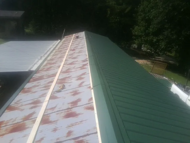 Old rusted panels beside newly installed green metal roofing — Wind Damage Roof Repair by Roofing Brothers in Notre Dame