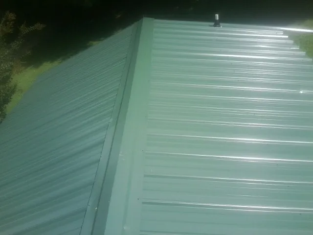 New green metal panels meeting at the ridge of a roof — Flat Roof Repair work by our crew in Notre Dame