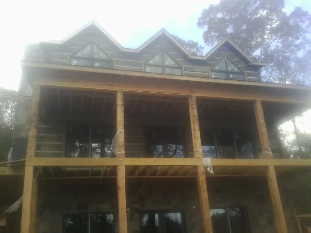 Dormers and porch framing on a large log home under construction — Roof Coating work by our crew in Notre Dame