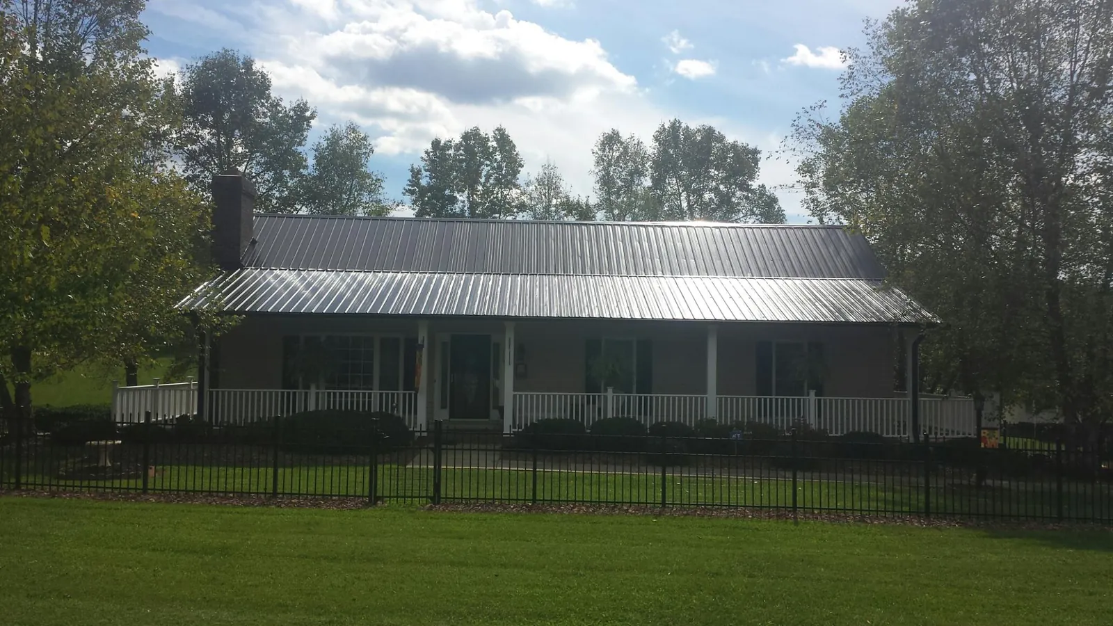 Gray metal roof on a brick ranch with a full width front porch — Gutter Guard Installation work by our crew in Notre Dame