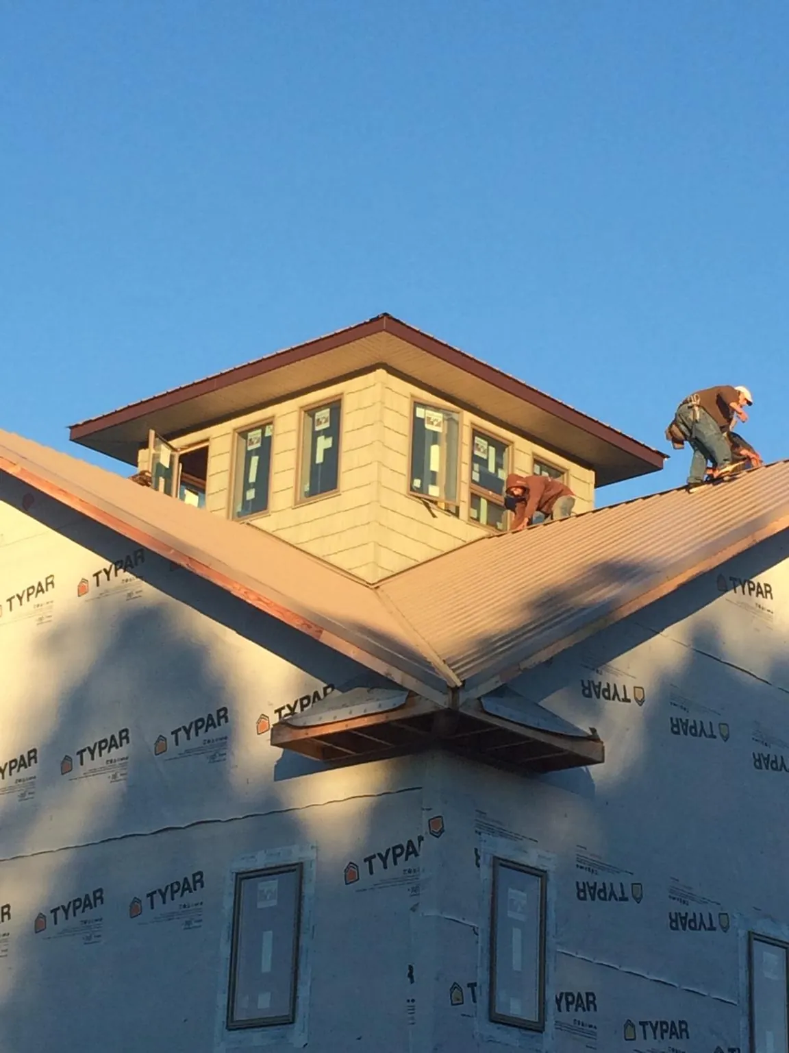 Roofers working around a rooftop cupola on a new metal roof at sunset — Roof Waterproofing in Notre Dame by Roofing Brothers